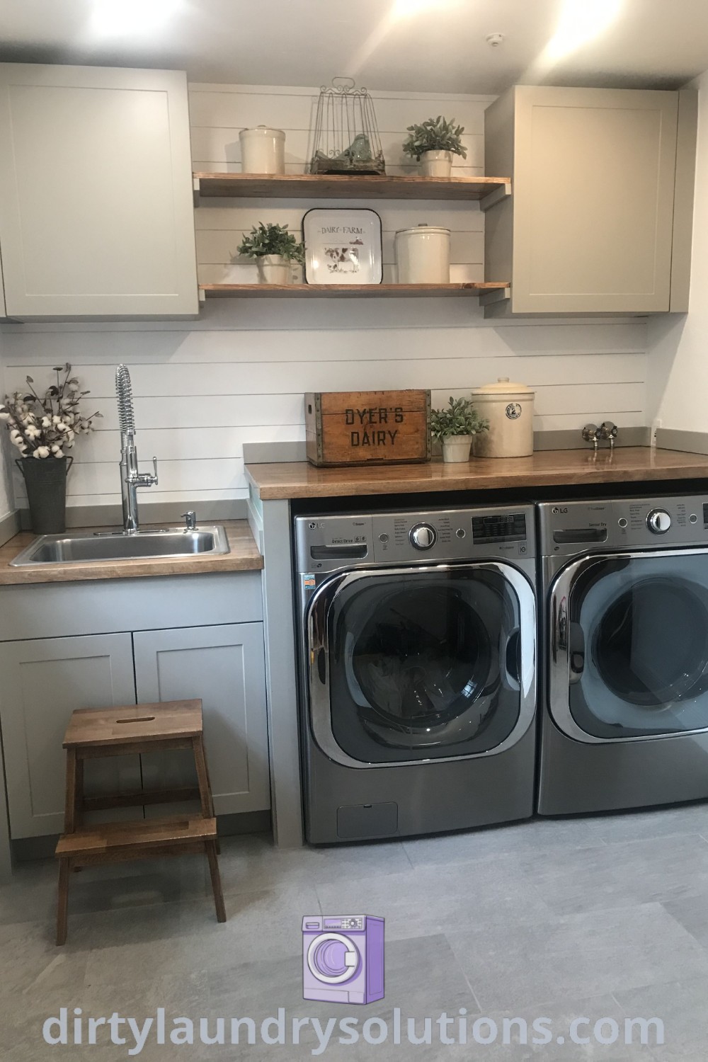 A modern rustic laundry room with a washer and dryer in a small space, open shelving above, and dark grey appliances, showcasing cozy design ideas and inspiring organization solutions. Discover more laundry room inspirations at dirtylaundrysolutions.com.