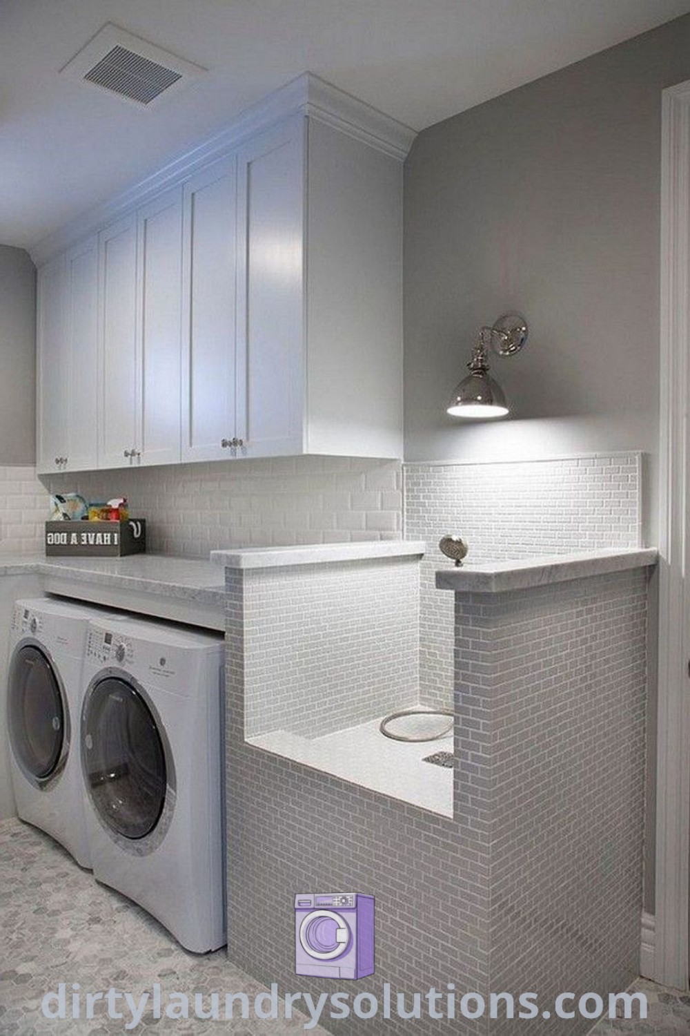 A white washer and dryer in a stylish laundry room with gray tile flooring, featuring pallet cabinets and shelves for organized storage. Discover unique ideas for small spaces at dirtylaundrysolutions.com.
