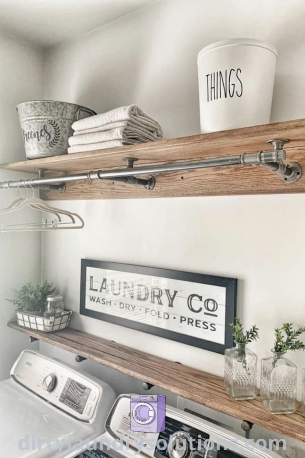 A laundry room featuring a washer and dryer with shelves above, a hanging bar between cabinets, and open shelving for organization. Discover functional solutions and inspiring ideas for your home at dirtylaundrysolutions.com.
