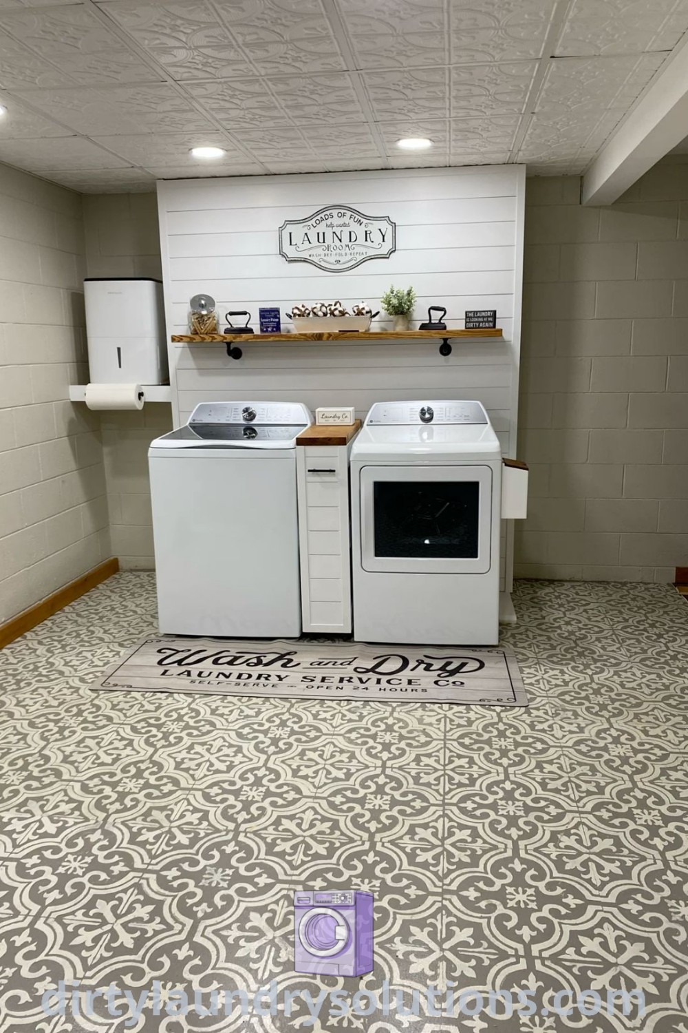 A basement laundry room with two washers and a dryer on a tile floor, showcasing stylish organizational solutions and cozy design ideas. Discover inspiring vintage aesthetics and functional updates for your space at dirtylaundrysolutions.com.