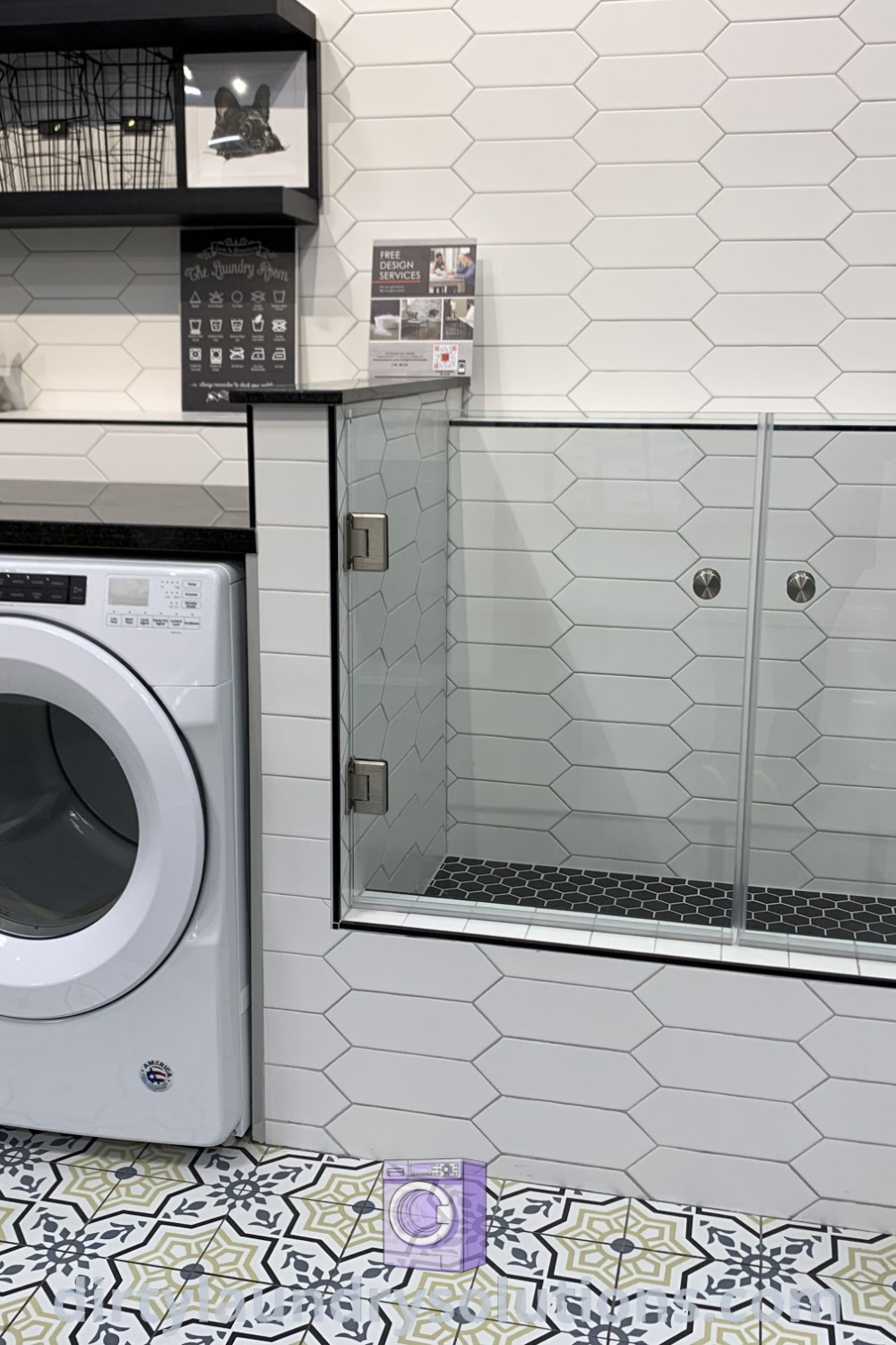A modern washer and dryer in a bathroom with tile flooring on the walls, showcasing a practical washing area and organized space. Discover more laundry room renovation ideas at dirtylaundrysolutions.com.