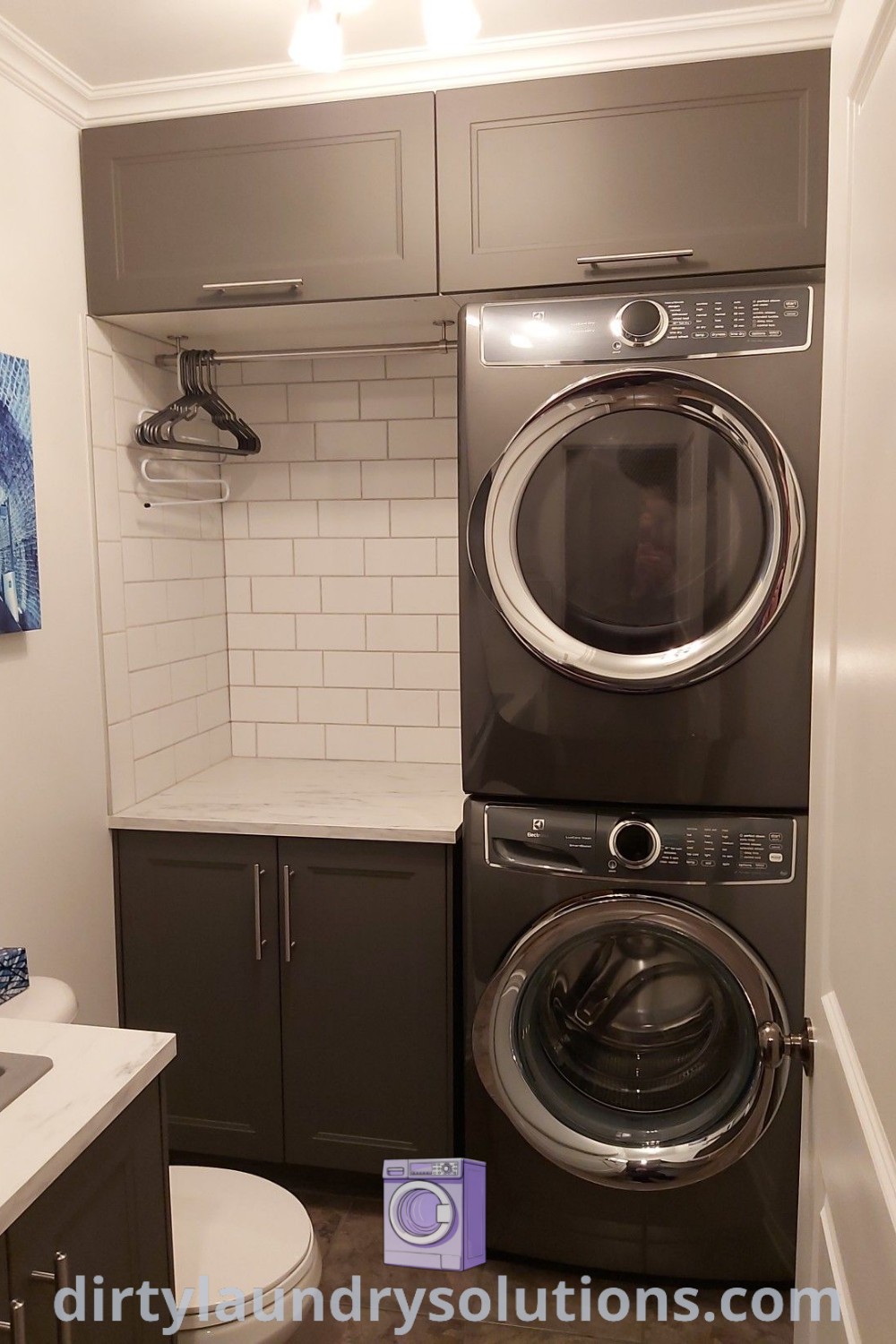 A stacked washer and dryer in a small room next to a sink with cabinets, showcasing organization ideas for small spaces. Discover inspiring laundry room solutions and cozy aesthetics at dirtylaundrysolutions.com.