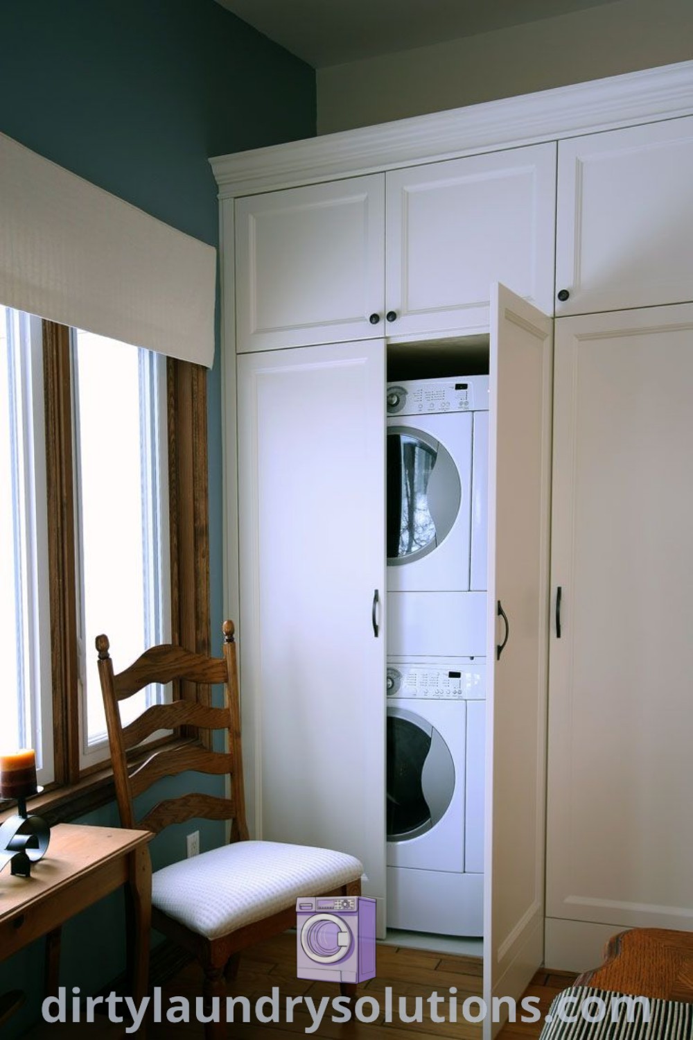 A cozy kitchen featuring a washer and dryer hidden behind cabinet doors, alongside a chair by a window, showcasing ideal organization ideas and design concepts for small spaces. Discover more tips and inspirations at dirtylaundrysolutions.com.