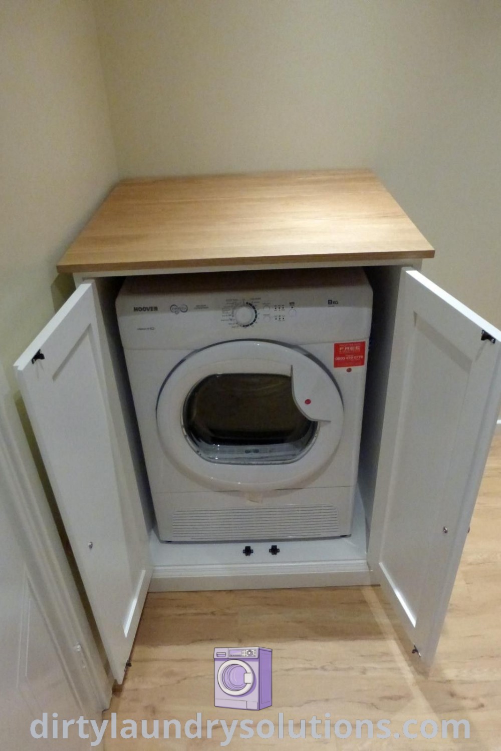 A washer and dryer in a stylish cupboard setting on wood flooring, showcasing DIY cupboard solutions and organization ideas for laundry rooms. Discover more inspiring designs and solutions at dirtylaundrysolutions.com.