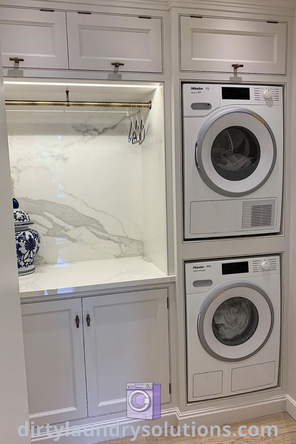 A white laundry room showcasing a washer and dryer with marble countertops, exemplifying stylish utility room designs and maximizing small spaces. Discover more inspiring ideas and organization tips for your home at dirtylaundrysolutions.com.