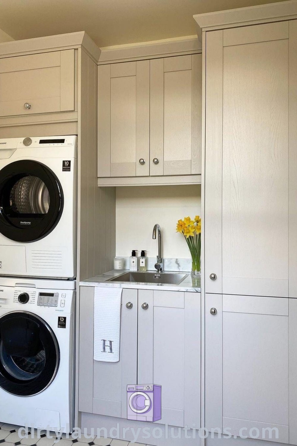 A utility room featuring a washer and dryer integrated into white cabinets, illustrating effective organization solutions for small spaces, enhanced by stylish design ideas. Find more inspiration at dirtylaundrysolutions.com.