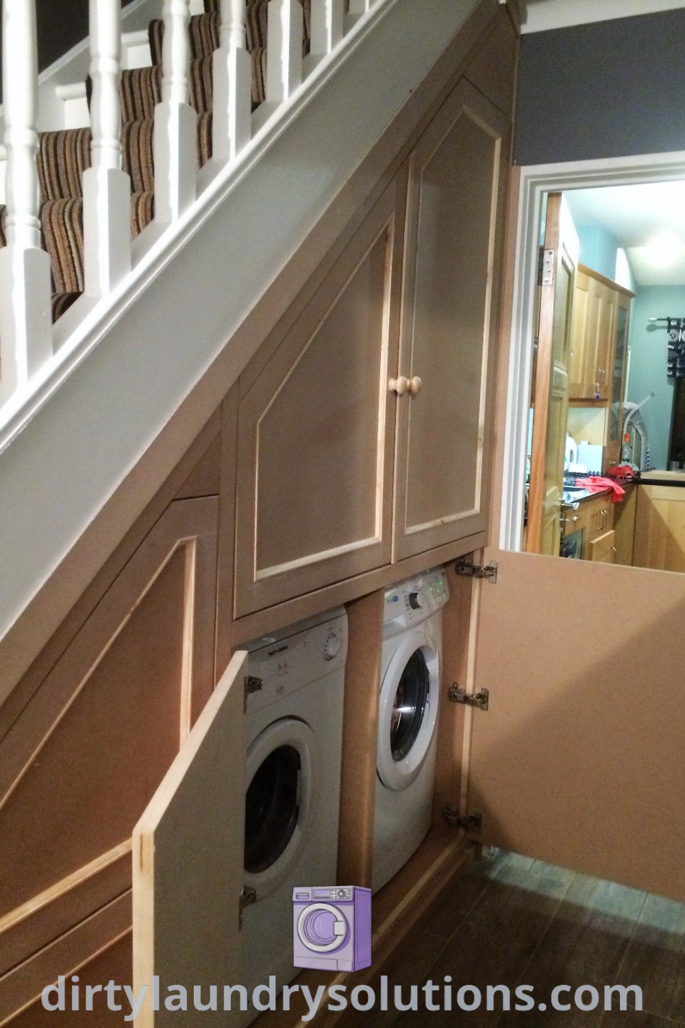 A cozy under stairs laundry room with a washer and dryer built into the wall, showcasing organization ideas for small spaces and unique designs. Discover more on dirtylaundrysolutions.com.