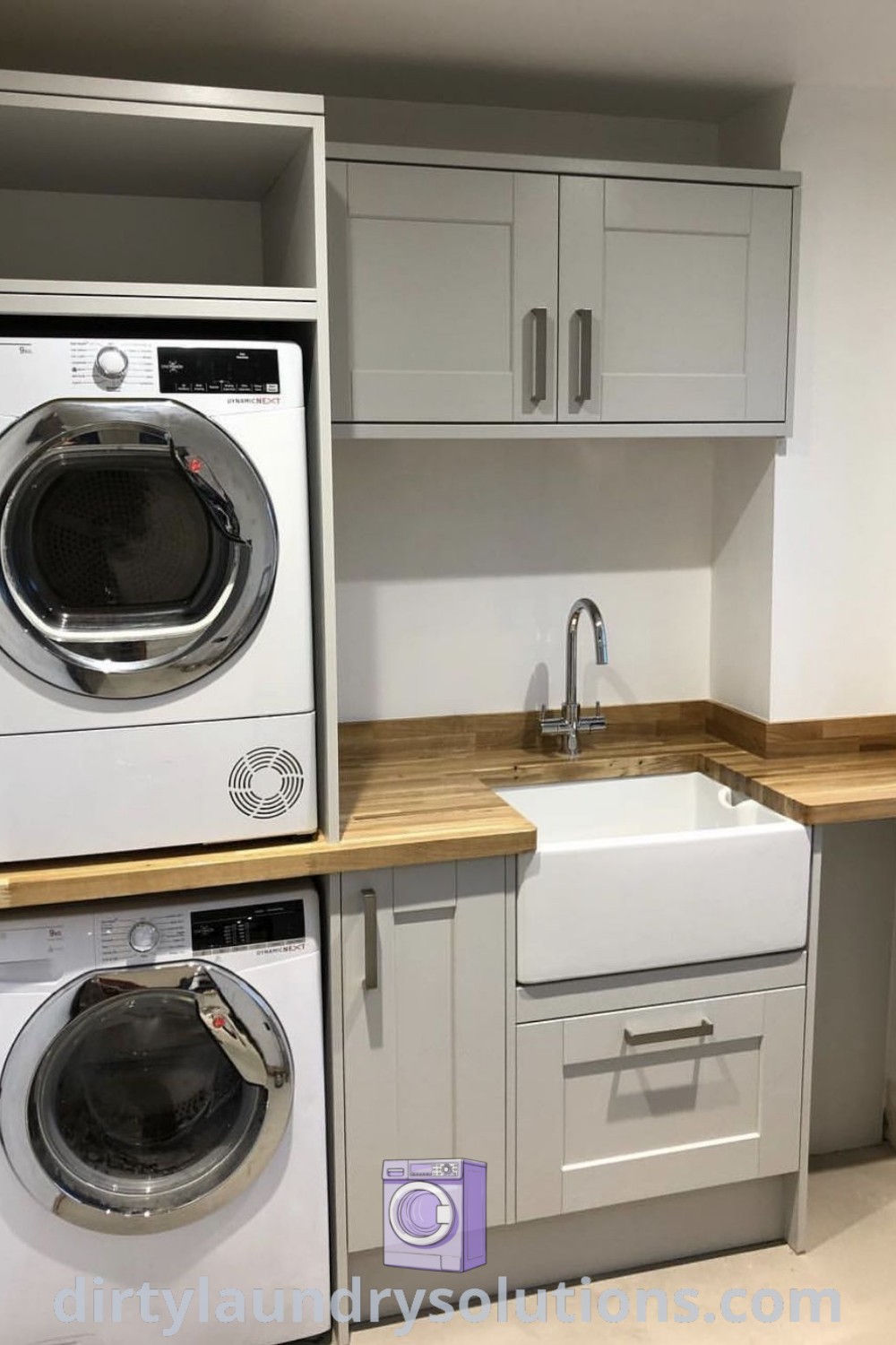 A washer and dryer in a kitchen on top of cabinets with wood shelves, showcasing practical utility room ideas and cozy aesthetics. Find more inspiring solutions for your laundry space at dirtylaundrysolutions.com.