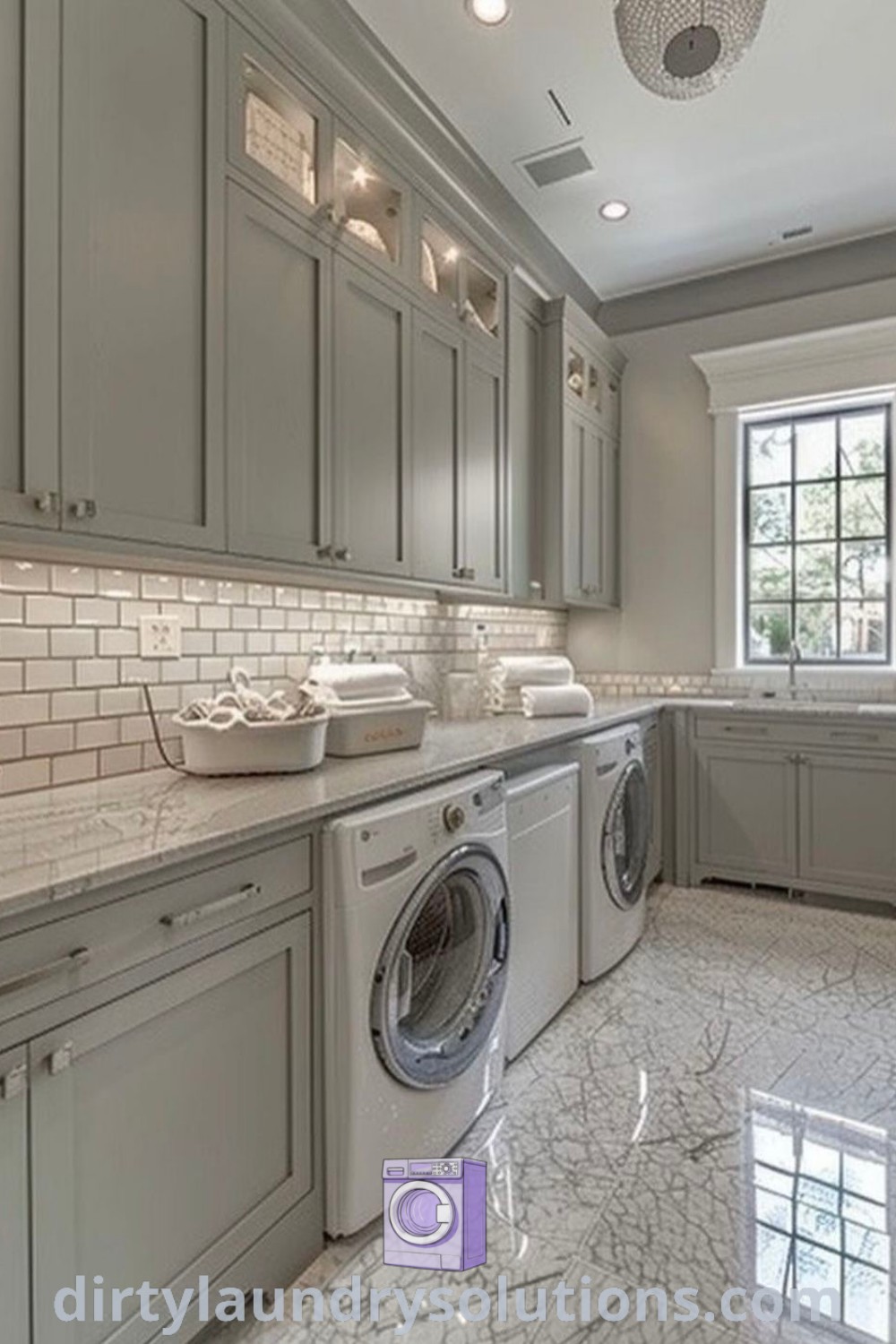A large kitchen laundry room with marble floors and gray cabinets, featuring to ceiling cabinets, ideal for maximizing storage and organization. Discover elegant laundry room solutions and inspiring ideas for your home at dirtylaundrysolutions.com.