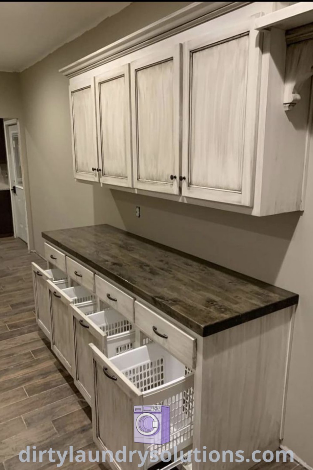 An empty laundry room with white cabinets and drawers, featuring baskets and a cozy nook, showcasing inspiring storage solutions and ideas for your home. Discover more stylish laundry room designs at dirtylaundrysolutions.com.