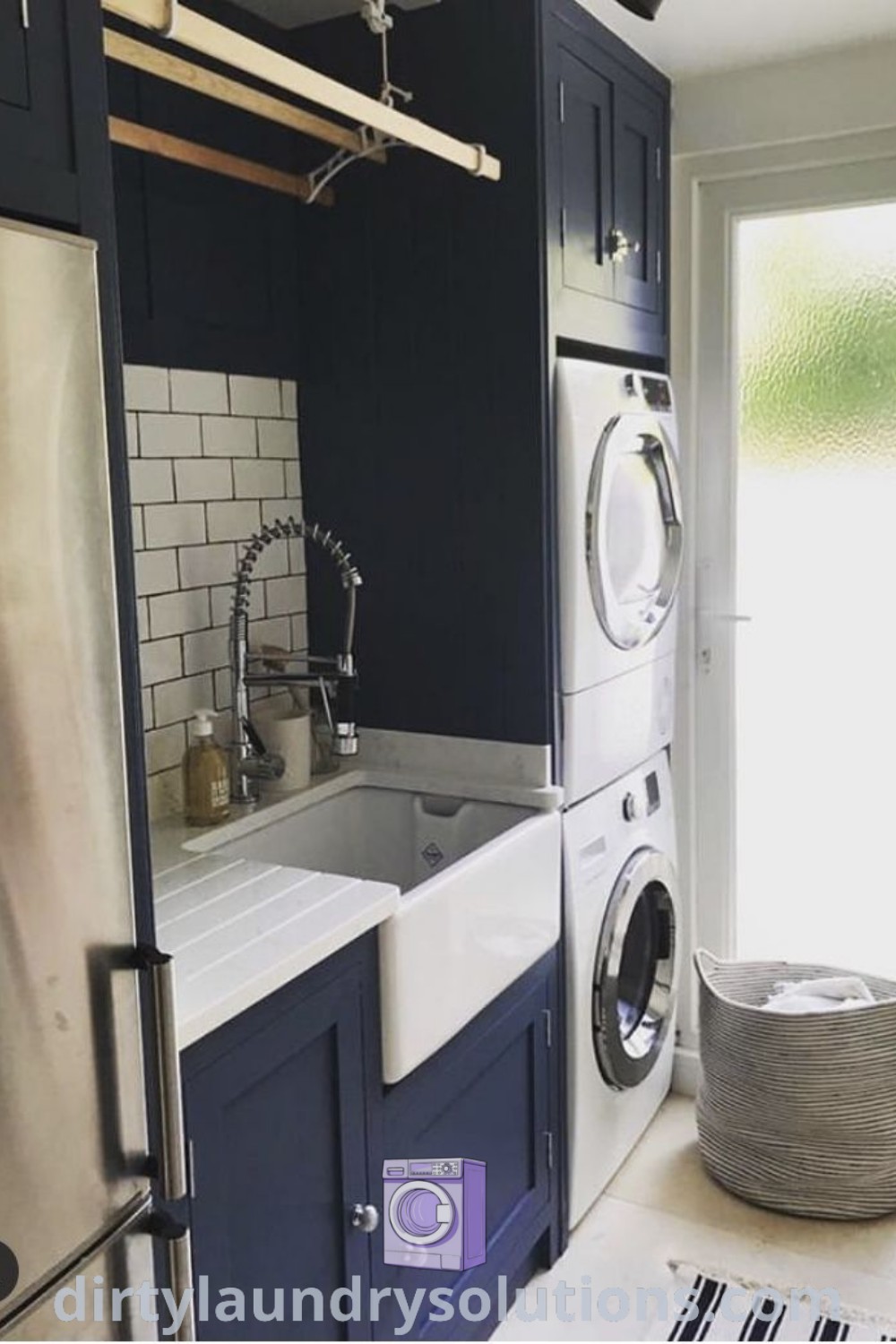 A cozy laundry room with a washer and dryer, dark blue cabinets, striped rugs, and a white sink, demonstrating effective organization ideas for small spaces. Explore more utility room inspirations and solutions at dirtylaundrysolutions.com.