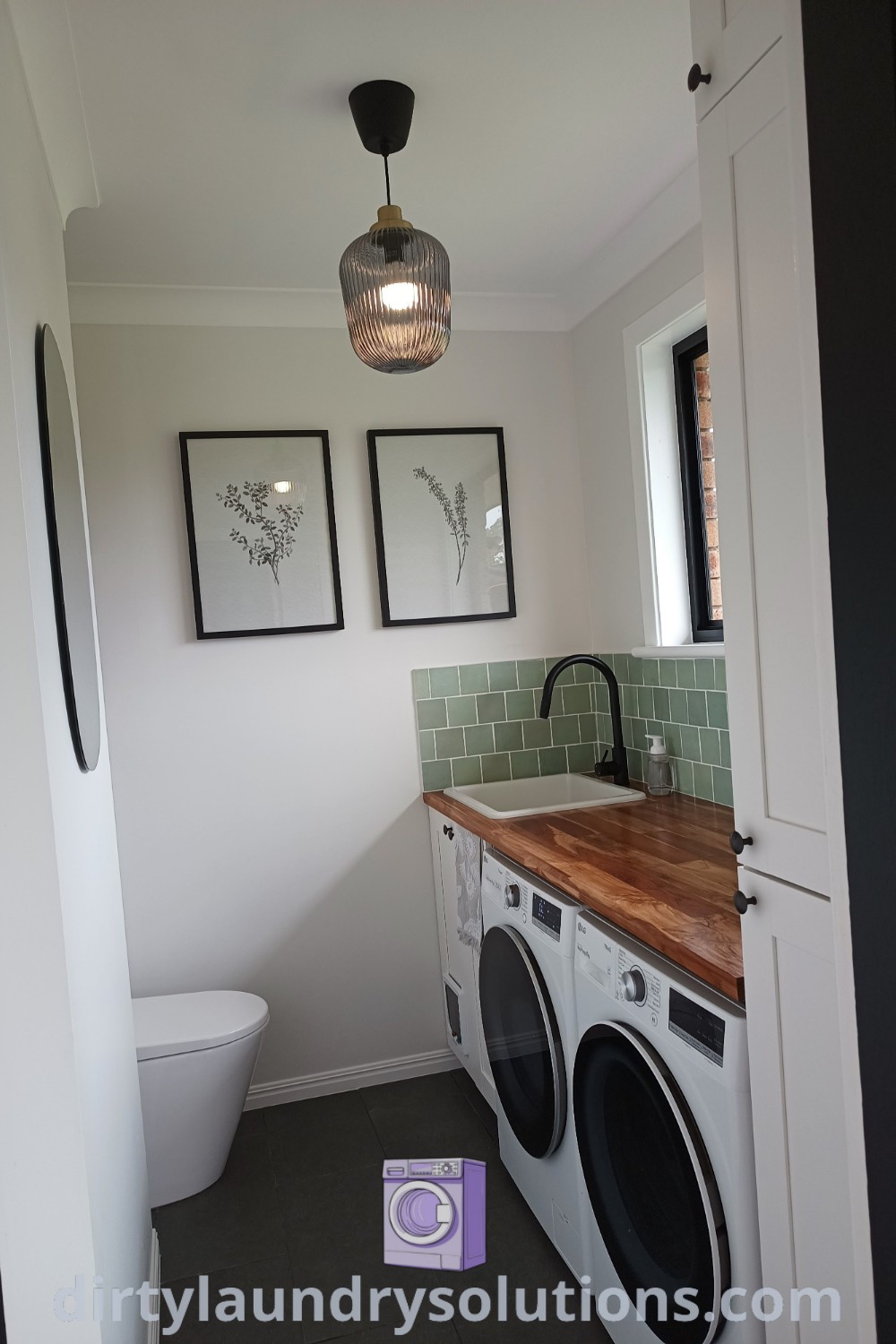 A cozy laundry bathroom combo featuring a washer and dryer with decorative pictures on the wall above, showcasing a practical design for a small full bathroom. Discover unique ideas and solutions for your home at dirtylaundrysolutions.com.