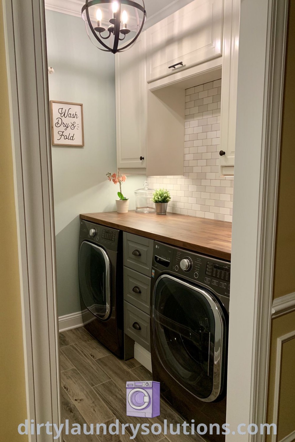 A small laundry room featuring a washer and dryer on wood flooring, showcasing organization ideas perfect for tiny houses and apartments. Discover more inspiring small space designs at dirtylaundrysolutions.com.