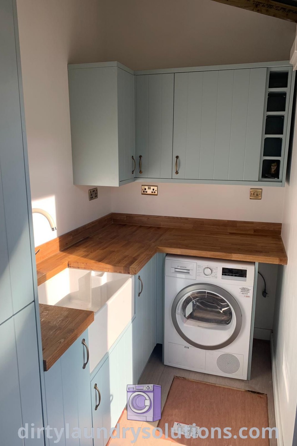 A small utility room with a washer and dryer, wooden countertops, and a window, showcasing cozy design ideas including garage conversion options and organizing solutions for homes, available at dirtylaundrysolutions.com.