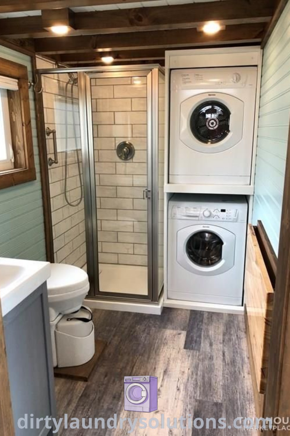 A small bathroom featuring a washer and dryer with wood flooring on the walls, illustrating cozy ideas for tiny house interiors. Discover more tiny house inspirations and design ideas at dirtylaundrysolutions.com.