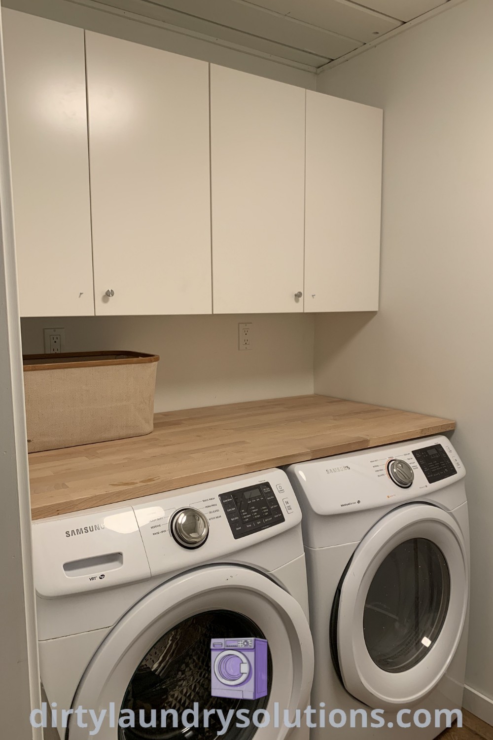 A compact laundry nook featuring a washer and dryer with white cabinets on the wall, designed for maximum organization and efficiency in small spaces. Discover inspiring designs and solutions for laundry room organization at dirtylaundrysolutions.com.