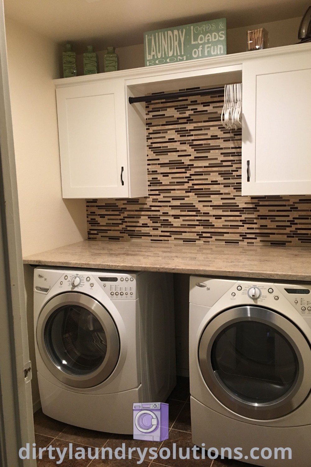 A cozy laundry room with a washer and dryer underneath built-in cabinets, showcasing smart storage ideas and a stylish design perfect for small spaces. Explore more laundry room makeovers at dirtylaundrysolutions.com.