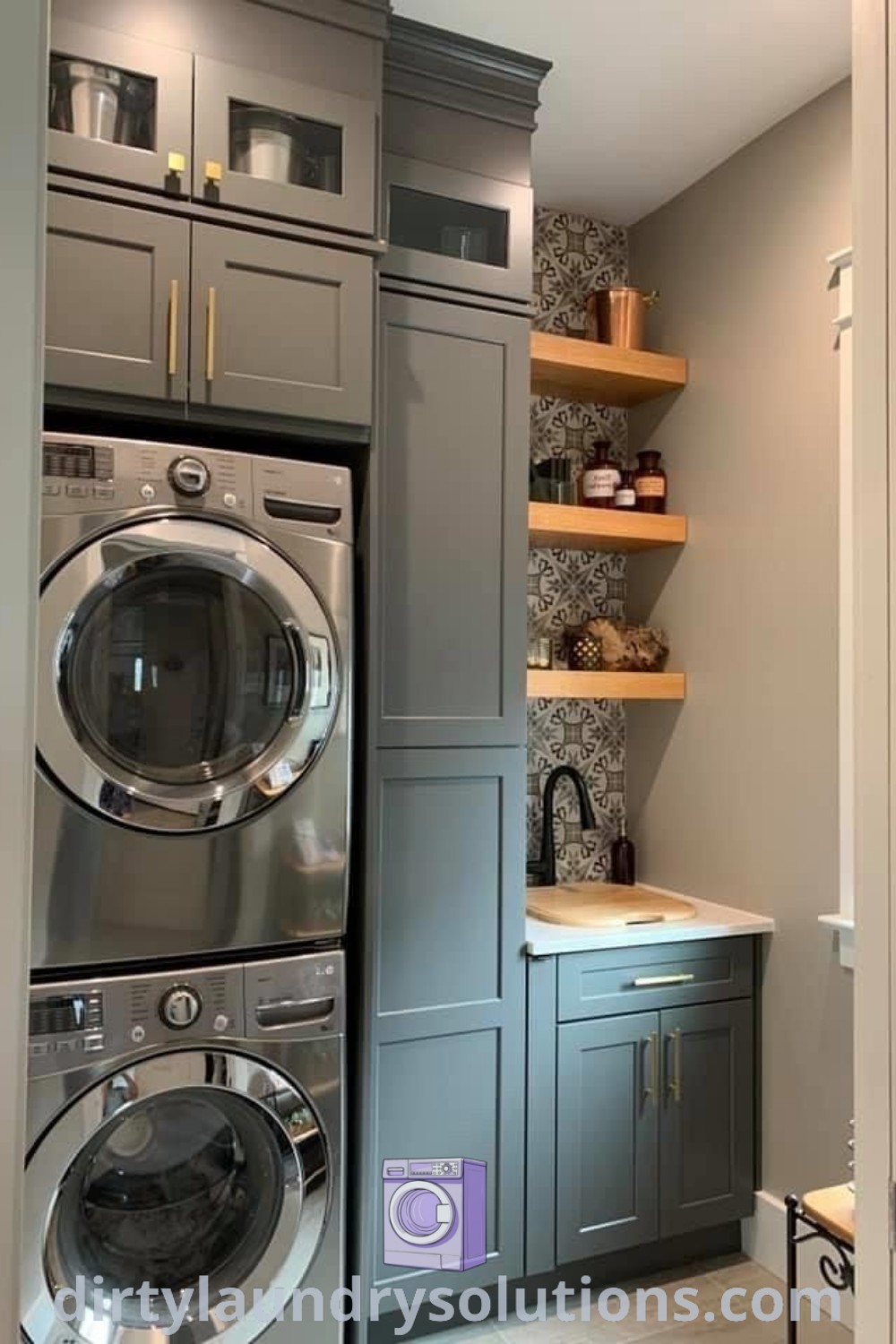A cozy small laundry room featuring a stacked washer and dryer with shelves on the wall, illustrating efficient laundry room layout designs and inspiring ideas for small spaces. Learn more about laundry room organization and design ideas at dirtylaundrysolutions.com.