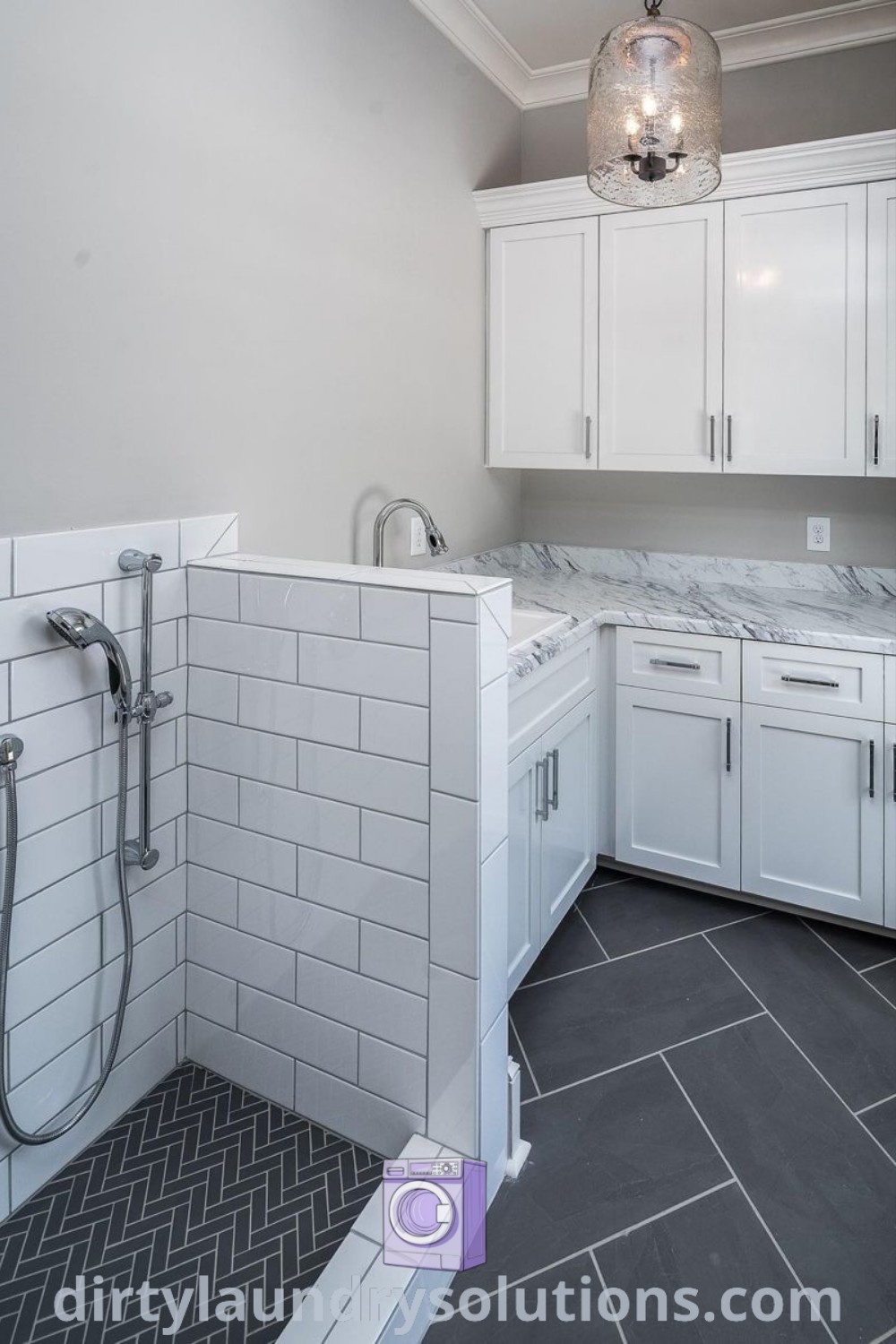 A dog wash laundry room with white cabinets, gray flooring, and two shower heads, perfectly designed as a dog bathing station. Discover inspiring design ideas for your home and more solutions at dirtylaundrysolutions.com.