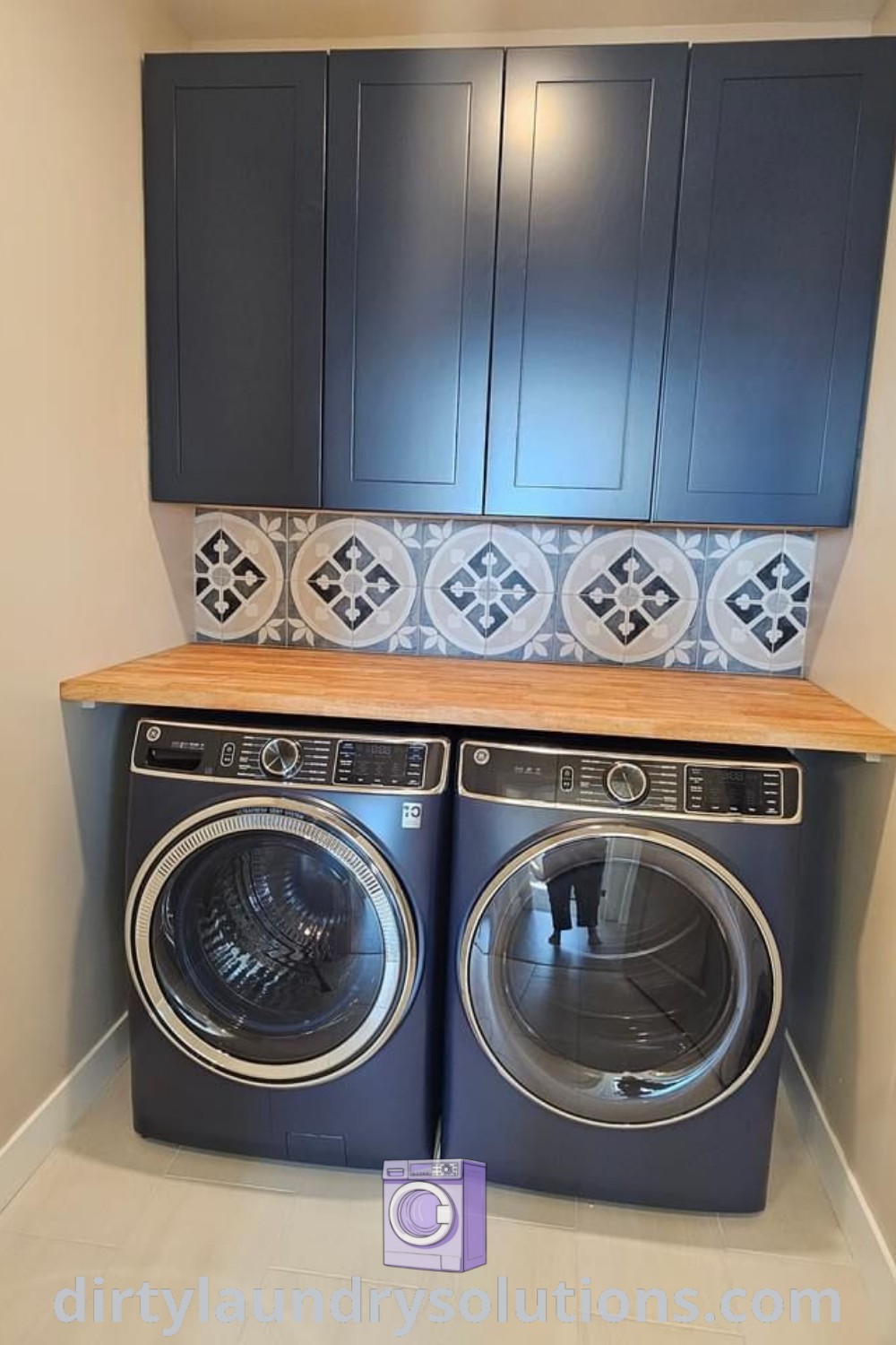 A navy blue washer and dryer in a stylish laundry room featuring blue cabinetry, a wood countertop, and patterned tile backsplash, showcasing unique ideas for cozy and organized spaces. Discover more inspiring designs at dirtylaundrysolutions.com.